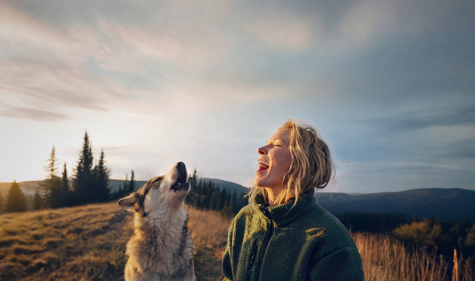 Eine junge Frau und ein großer Hund in einer weiten Landschaft sehen aus, als würden sie miteinander wie Wölfe heulen
