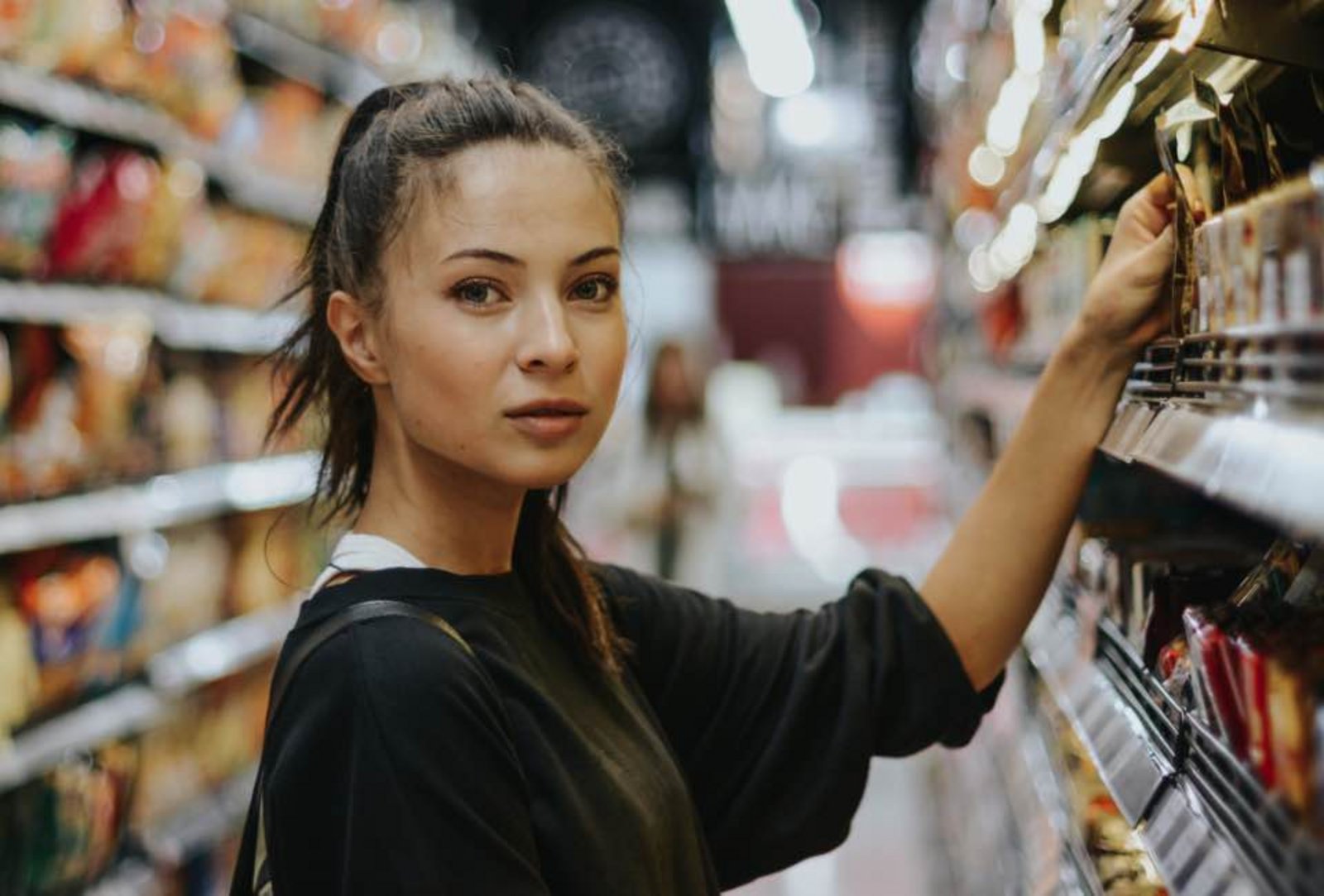 Eine junge Frau am Supermarktregal.