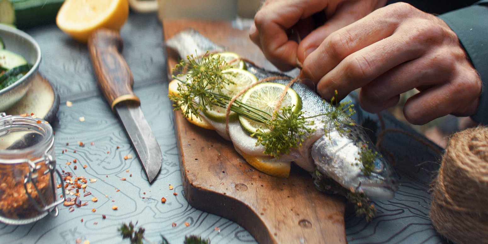 Outdoor geht überall: Junge Menschen feiern mit Genuss eine Rooftop-Party, eine Familie auf dem Weg zum Wald-Picknick, eine Forelle wird direkt am Flußufer gegrillt.