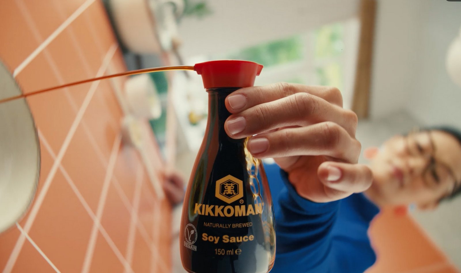 Closeup auf einen Kikkoman Dispenser, aus dem Sojasauce gegossen wird.