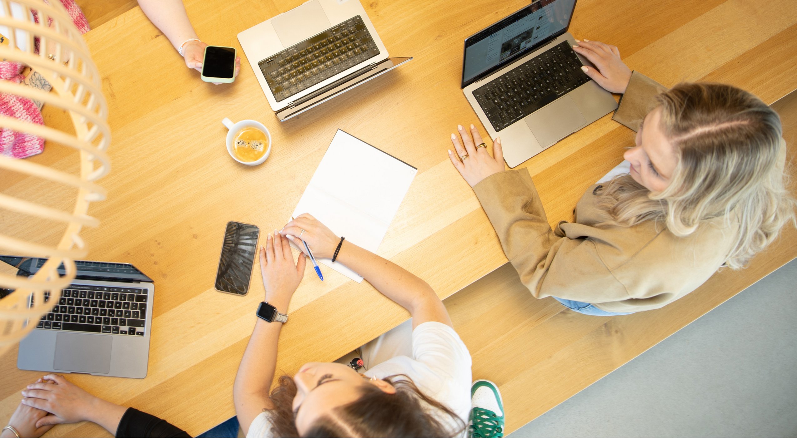 Topview auf einen modernen Schreibtisch, Menschen im Gespräch.