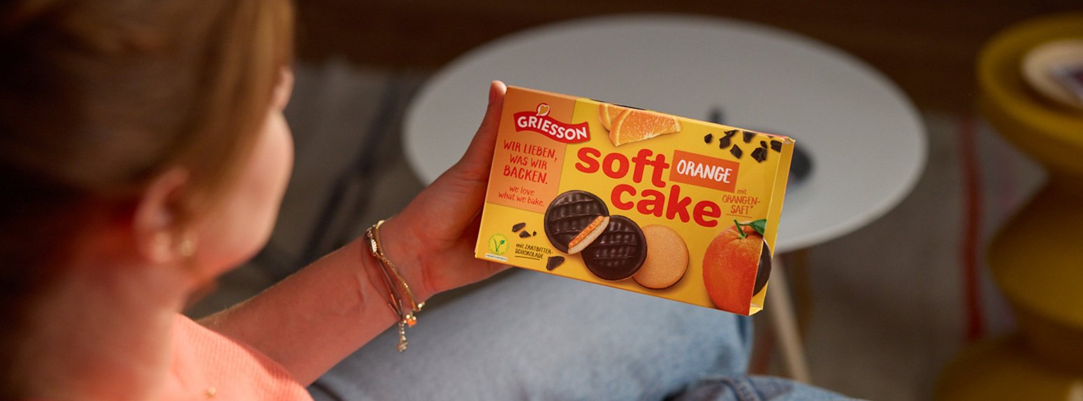 Frau hält prominent die Packung Soft Cake ins Bild.