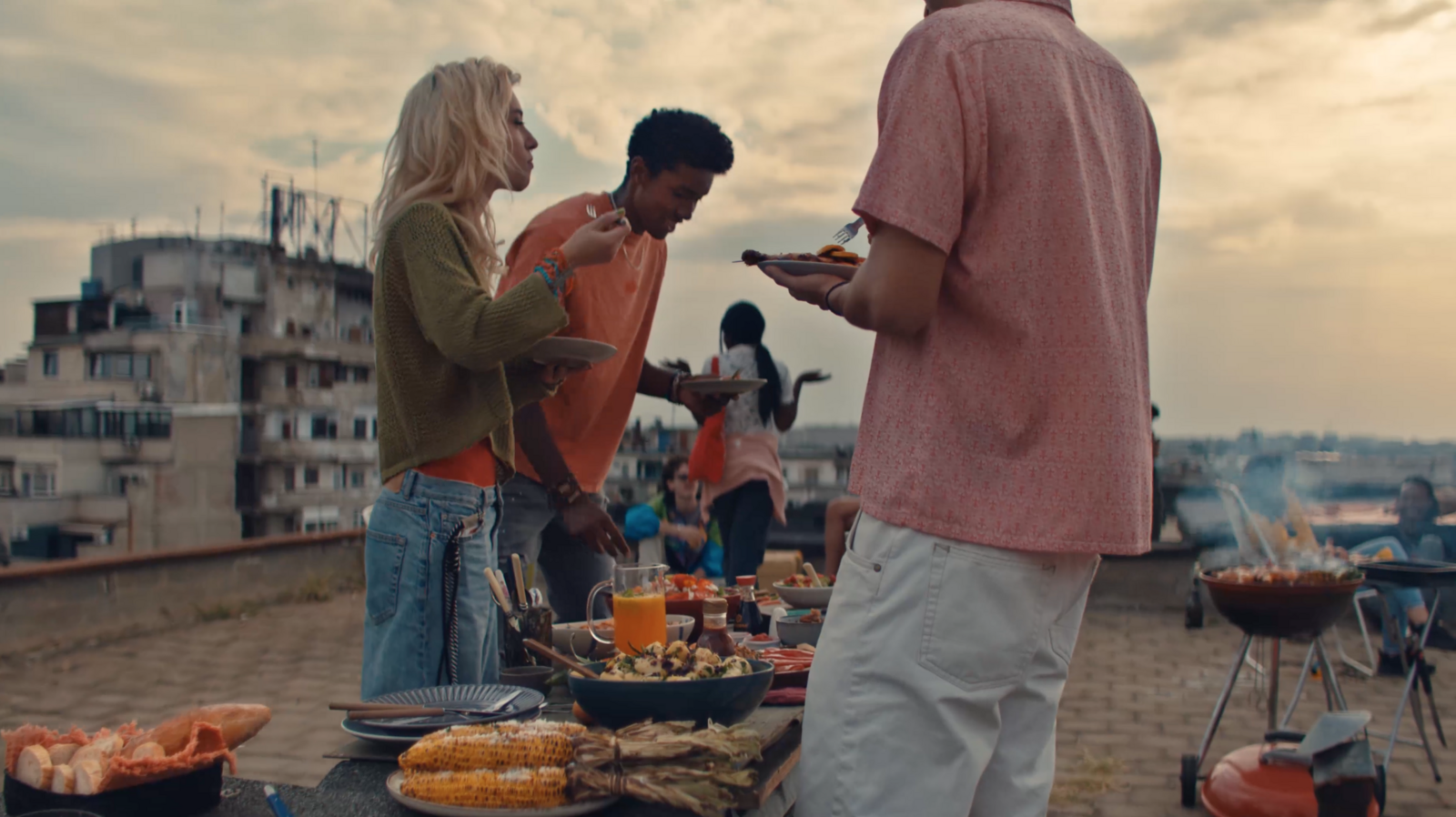 Outdoor geht überall: Junge Menschen feiern mit Genuss eine Rooftop-Party, eine Familie auf dem Weg zum Wald-Picknick, eine Forelle wird direkt am Flußufer gegrillt.