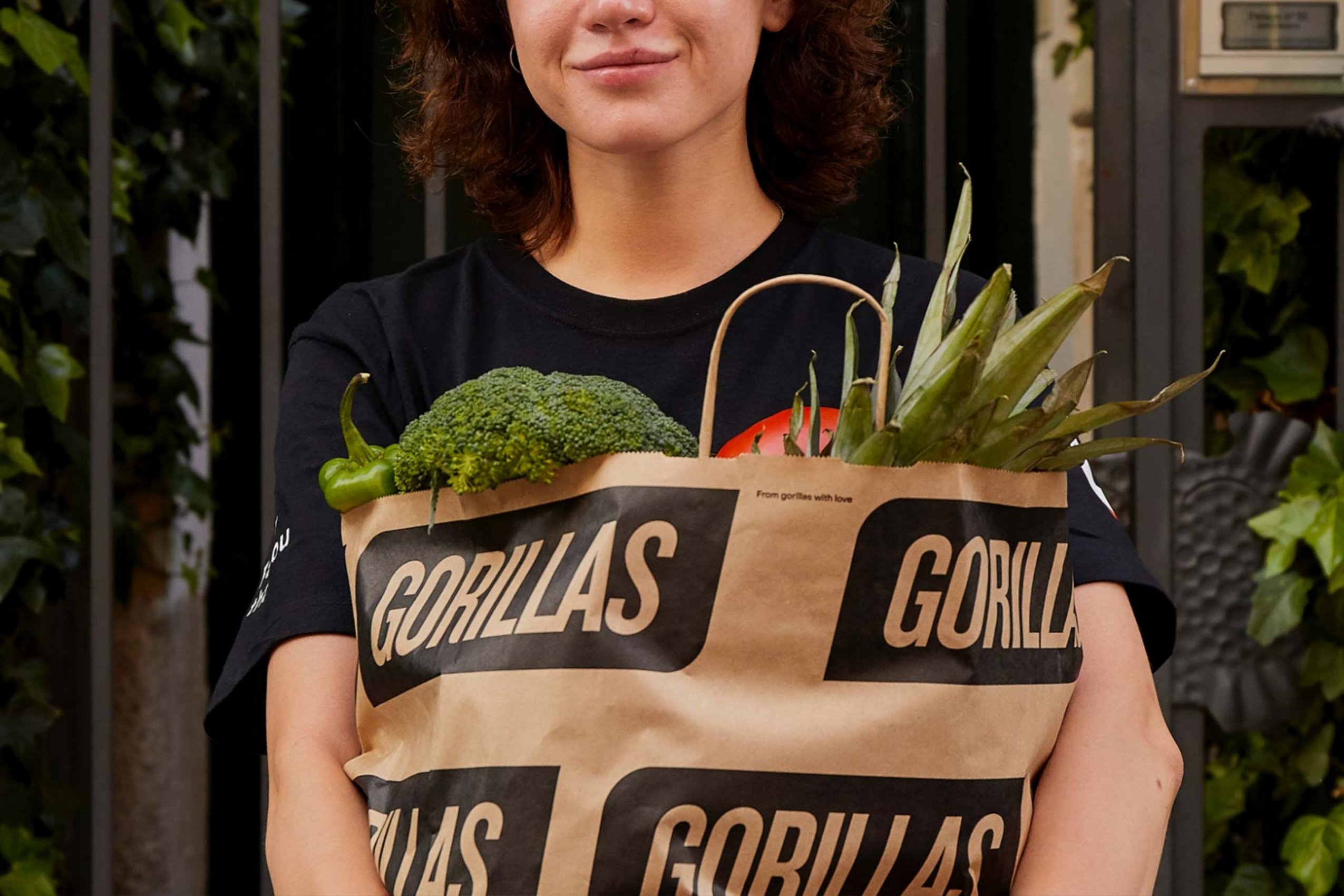 Eine Frau mit einer vollen Papiereinkaufstüte im Arm. 